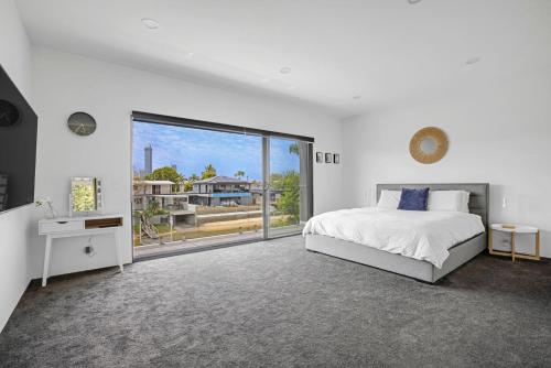 a white bedroom with a bed and a large window at Urban Hideaway - Stay 4 Pay 3 in Gold Coast