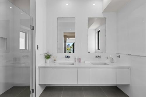 a white bathroom with two sinks and a mirror at Wanderlust heated pool rooftop deck in Gold Coast