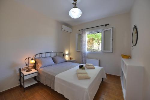a white bedroom with a bed and a window at Anastasia Home in Triandáros