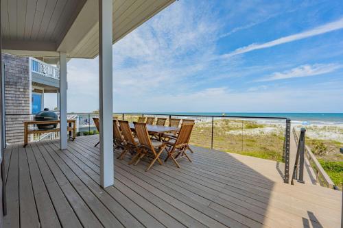 a wooden deck with a table and chairs and the ocean at Seaview Serenity - Team Joseph Ellen in Jacksonville Beach