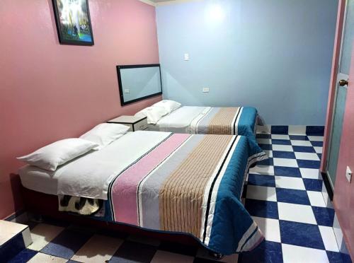 two beds in a room with a checkered floor at Hospedaje LA RESIDENCIA in Ayacucho