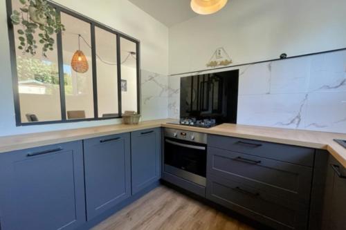 a large kitchen with blue cabinets and a stove at Spacious cocoon with pool in La Rochelle in La Rochelle