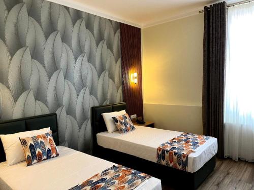 a hotel room with two beds and a wall mural at Hotel Santal in Bukhara