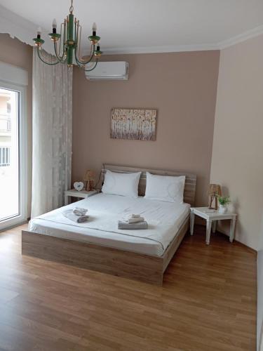 a bedroom with a bed with white sheets and a chandelier at Kavala Penthouse in Kavála
