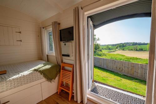 a room with a bed and a window with a view at Hazel Boutique Shepherds Hut Cotswolds in Cirencester