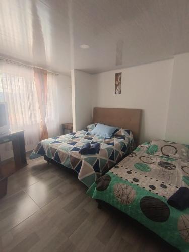 a bedroom with two beds and a desk and window at Casa Bercel in Choachí