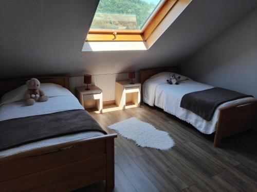 a attic bedroom with two beds and a window at "Parenthèse Alsacienne" in Luttenbach-près-Munster