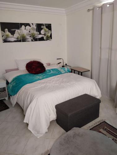a bedroom with a bed with a ottoman next to it at Dar Fouzia in Hammamet Sud