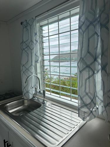 a kitchen sink and a window with a view of the ocean at Trinity Point Hillside Villa, beach & sunset views in Bequia