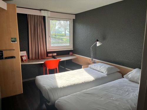 a hotel room with two beds and a desk and a window at ibis Lorient Centre Hôtelier in Caudan