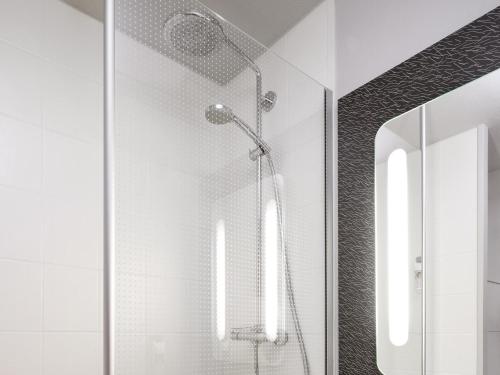 a shower in a bathroom with a glass wall at Ibis Roanne Le Coteau Hotel Restaurant in Le Coteau