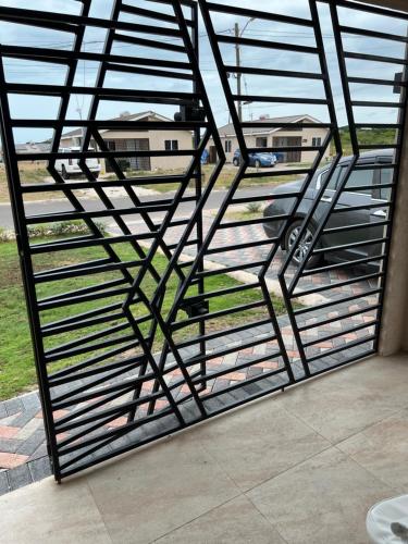 a metal screen door with a view of a field at Comfort Rest - Whim in Old Harbour