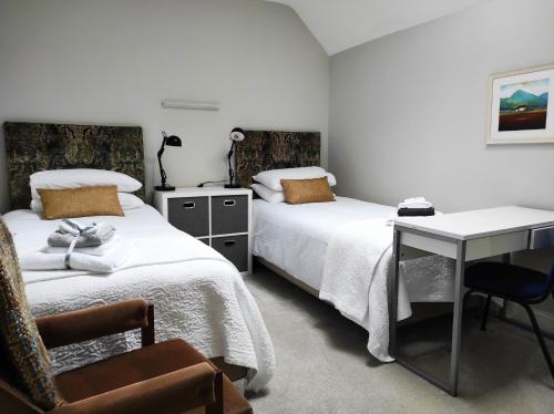 a bedroom with two beds and a desk and a chair at Glendalough Sanctuary in Brockagh