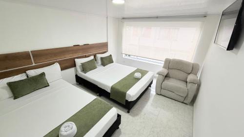 a hotel room with two beds and a chair at Casa Mama Hotel in Manizales