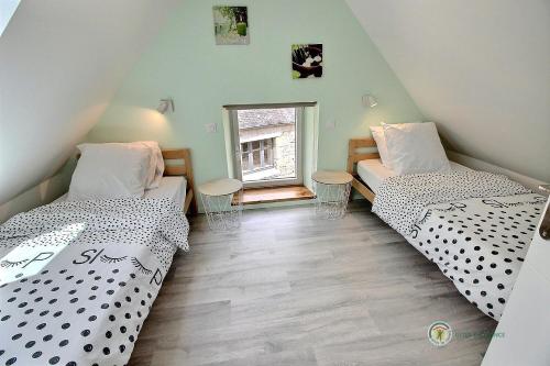 two beds in a room with a window at Ty feuteun in Lanvellec