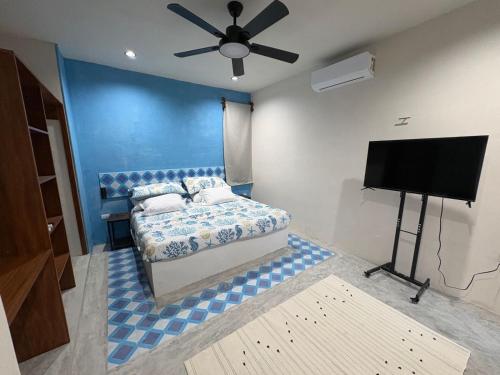 a bedroom with a bed and a flat screen tv at Casa Laura Azul in El Cuyo