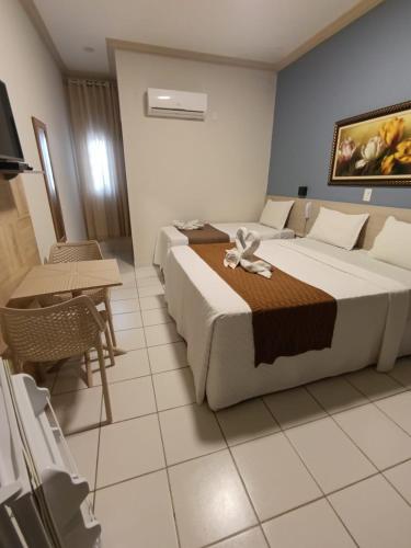 a hotel room with two beds and a table at Pousada Maragolfinho in Maragogi