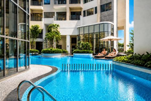a hotel swimming pool with two people sitting on chairs in front of a building at YAKA Residences - Trizen Luxury Apartments in Colombo
