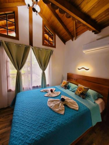 a bedroom with a blue bed with two towels on it at Arenal Sweet Cabins in Fortuna