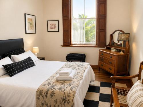 a bedroom with a bed and a dresser and a window at Albert Manor guest house in Ladismith