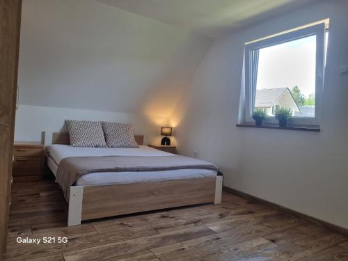 a white bedroom with a bed and a window at Domek na Sowiej in Kłodzko