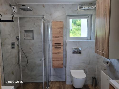 a bathroom with a shower and a toilet and a window at Domek na Sowiej in Kłodzko