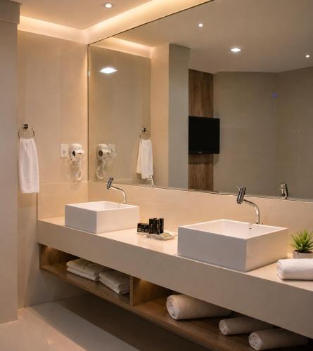 a bathroom with two sinks and a large mirror at Granterrara Hotel in Jequié