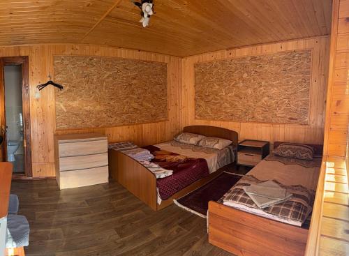 a bedroom with two beds in a wooden room at Садиба «Під ліском» in Pulʼmo