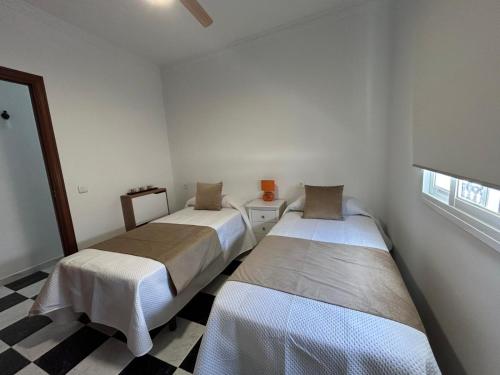 two beds in a white room with a checkered floor at Isabella Chipiona in Chipiona