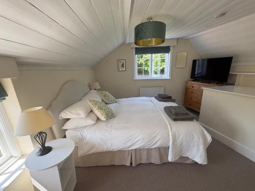 a bedroom with a white bed and a window at Stunning 3 bedroom 3 bath self catering cottage nr Stonehenge, Salisbury, Longleat, Avebury and Bath, Short walk to lovely village pub in Pewsey
