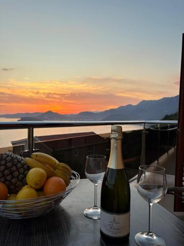 a bottle of wine and a bowl of fruit and wine glasses at Sunset Residence Blizikuce in Budva
