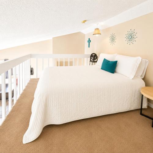 a bedroom with a white bed and a cross on the wall at The Little Penthouse in Lake Ozark