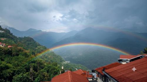 a rainbow in the sky over a city at ANG'S Retreat By WINGS Expolores in Gangtok