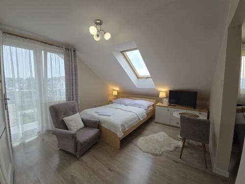 a bedroom with a bed and a tv and a chair at Mirato in Władysławowo