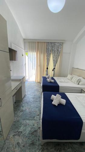 two beds in a hotel room with towels on them at orhan pansiyon in Çeşme