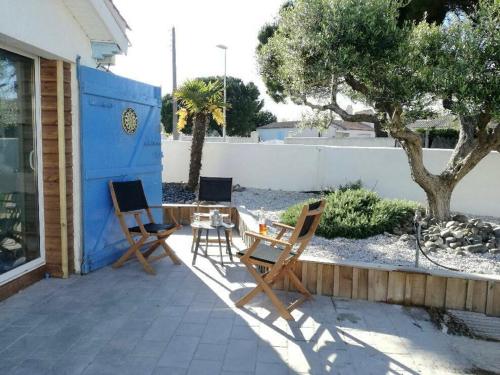 a patio with two chairs and a table in front of a house at L'Olivier des Dunes in Saint-Georges-dʼOléron