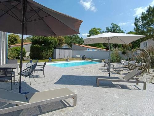 a patio with chairs and umbrellas and a pool at L'Olivier des Dunes in Saint-Georges-dʼOléron