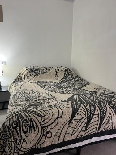 a bed with a black and white blanket on it at Hummingbird Haven in Uvita