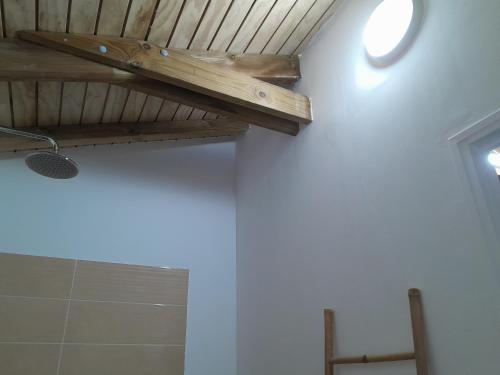 a bathroom with white walls and a wooden ceiling at Studio LAVANDES in Lamentin
