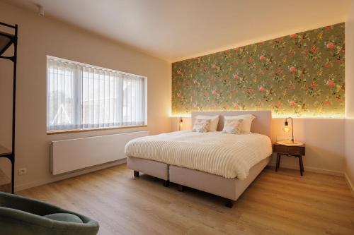 a bedroom with a bed with a floral painting on the wall at The Edewallenaar in Kortemark