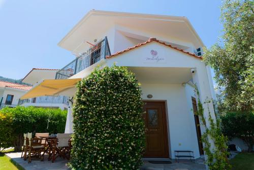 a white house with a hedge in front of it at Villa Nostalgia in Skala Potamias
