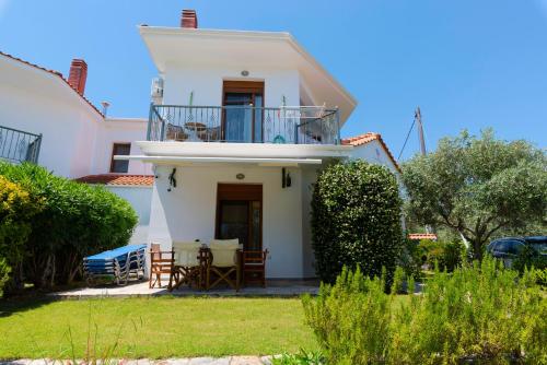 a white house with a balcony and a table at Villa Nostalgia in Skala Potamias