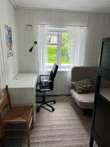 a room with a desk and a couch and a window at Small Cozy apartment with Wi-Fi in Tjørhom