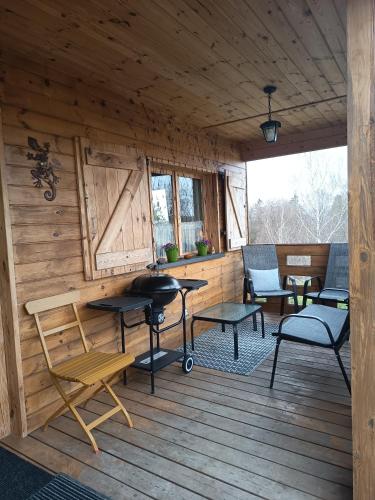 a porch of a cabin with chairs and tables at Leśna Chatka Kotlina Kłodzka in Kłodzko