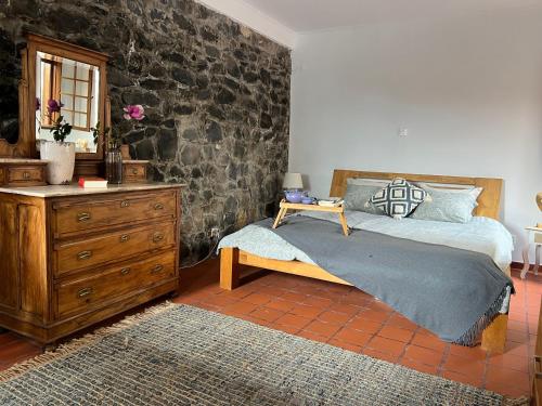 a bedroom with a bed with a wooden dresser and a dresser at Casa das Flores Funchal in Funchal