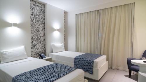 a hotel room with two beds and a sink at Golden Tower Maracanaú by Fênix Hotéis in Maracanaú