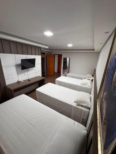 a room with three beds and a flat screen tv at Pousada Recanto das Chalanas in Corumbá
