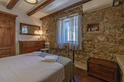 a bedroom with a bed and a stone wall at House Vila Ana in Lopar