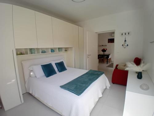 a white bedroom with a white bed with blue pillows at La casa dei gelsomini in Alassio