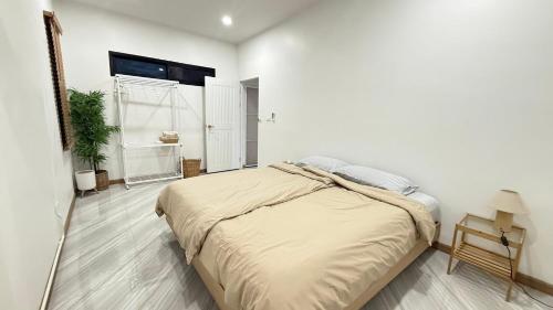 a bedroom with a large bed in a white room at Home No 5 in Ratchaburi